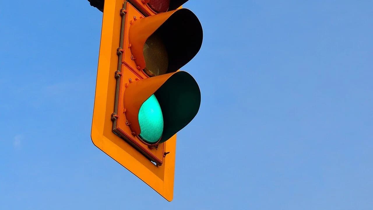 Close-up of a traffic light showing a glowing green light against a clear blue sky